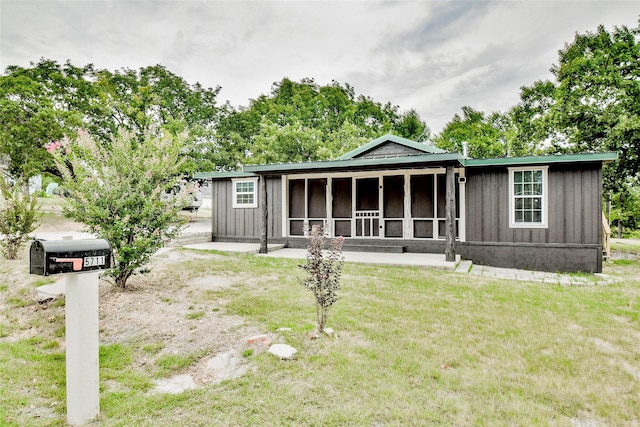 rear view of property featuring a sunroom and a lawn