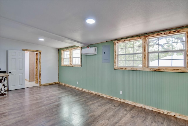 empty room featuring hardwood / wood-style flooring, electric panel, and a wall mounted AC