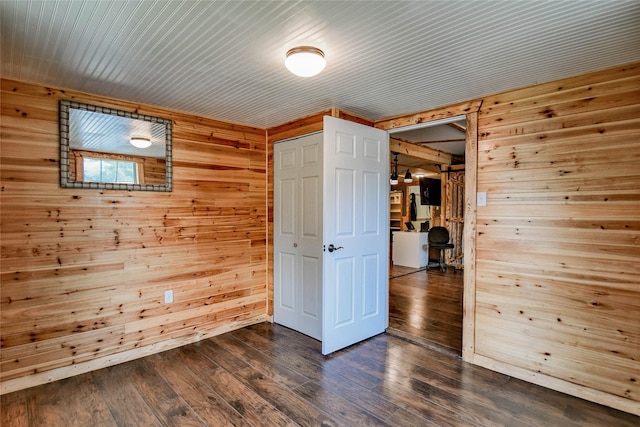 empty room with dark hardwood / wood-style floors and wood walls