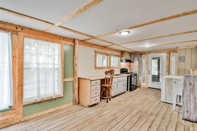 kitchen featuring black gas range, light hardwood / wood-style flooring, and custom range hood