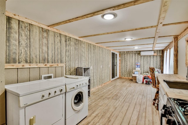 washroom with light wood-type flooring, an AC wall unit, independent washer and dryer, and wood walls