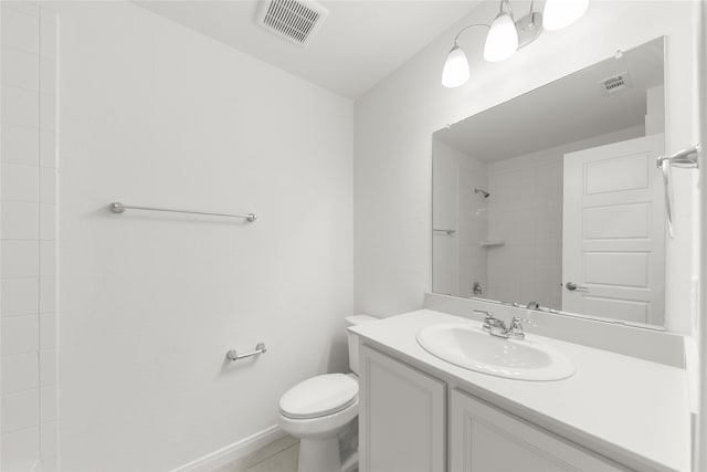 bathroom featuring tile patterned flooring, vanity, toilet, and tiled shower