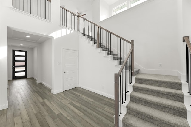 stairway featuring hardwood / wood-style floors, a towering ceiling, and ceiling fan