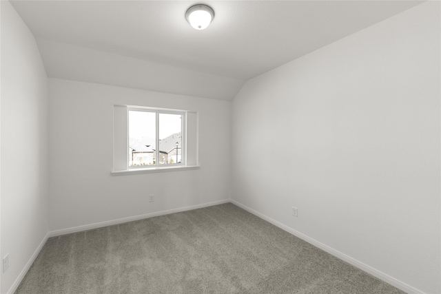 carpeted spare room featuring vaulted ceiling