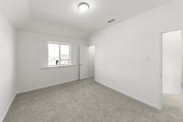 unfurnished room featuring light carpet and vaulted ceiling