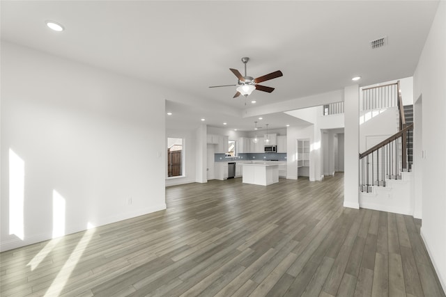 unfurnished living room with hardwood / wood-style floors, ceiling fan, and a healthy amount of sunlight