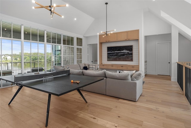 living room with high vaulted ceiling, light wood-type flooring, and an inviting chandelier