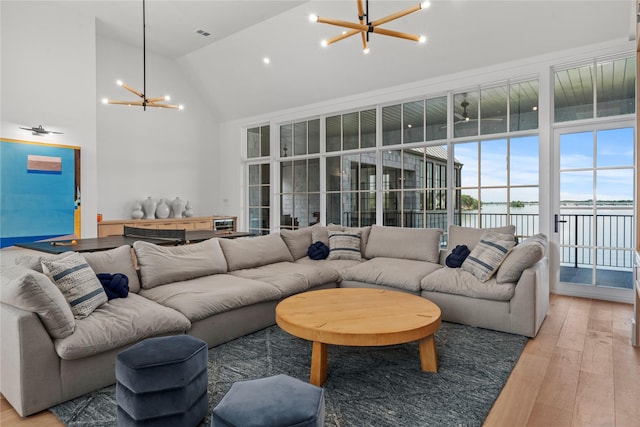 living room with an inviting chandelier, high vaulted ceiling, and hardwood / wood-style flooring