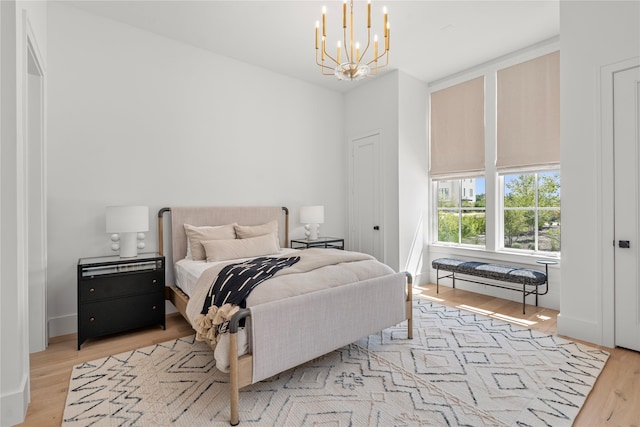 bedroom featuring an inviting chandelier and light wood-type flooring