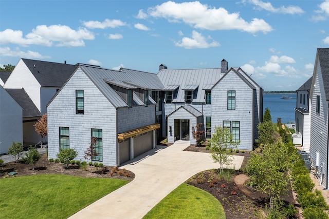 view of front facade featuring a garage, a water view, and a front lawn