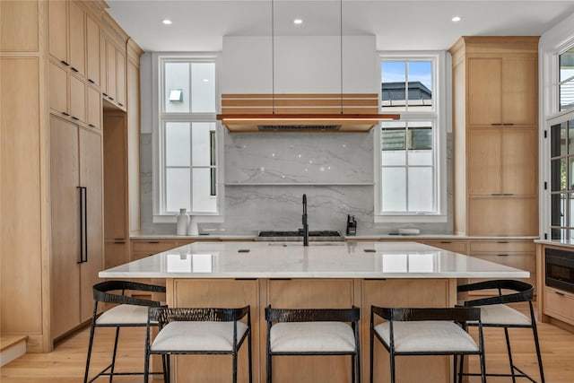 kitchen featuring an island with sink, a breakfast bar area, and light hardwood / wood-style flooring