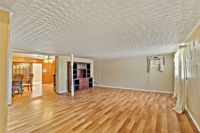 unfurnished living room featuring a wall mounted air conditioner, light hardwood / wood-style floors, and ceiling fan