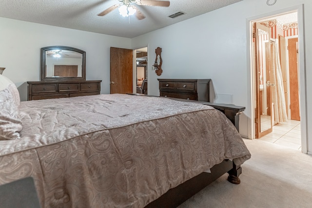 bedroom with light colored carpet, ensuite bathroom, a textured ceiling, and ceiling fan