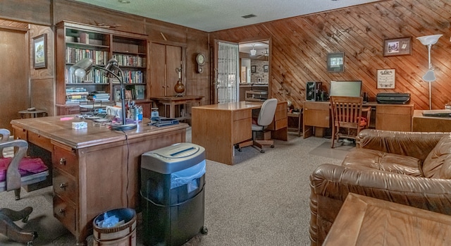 office area with light carpet, wooden walls, and a textured ceiling