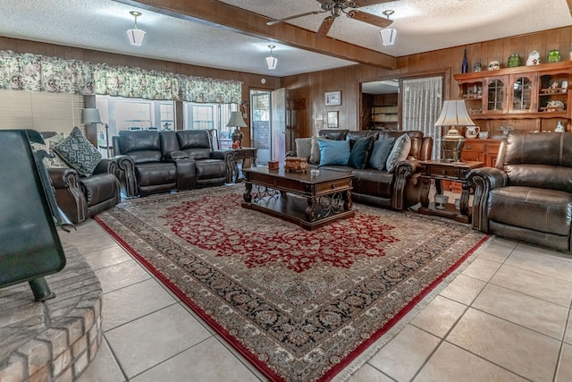 living room featuring ceiling fan, wood walls, light tile patterned floors, and a textured ceiling