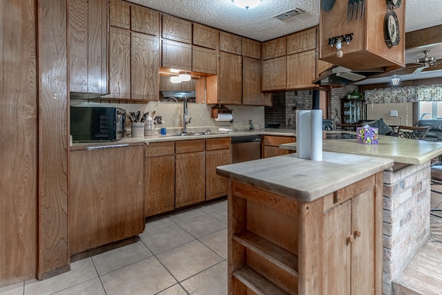 kitchen with dishwasher, a textured ceiling, tasteful backsplash, and light tile patterned floors