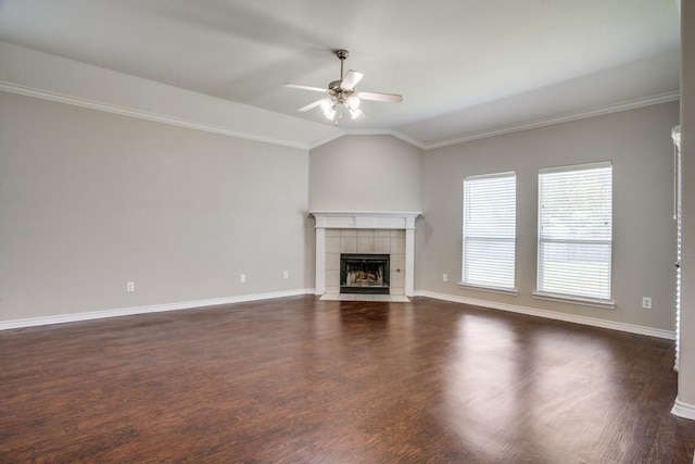 unfurnished living room with lofted ceiling, dark wood-type flooring, a tile fireplace, ceiling fan, and ornamental molding