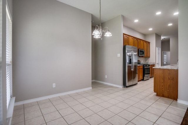 kitchen with stainless steel appliances, light stone counters, a chandelier, decorative light fixtures, and light tile patterned floors