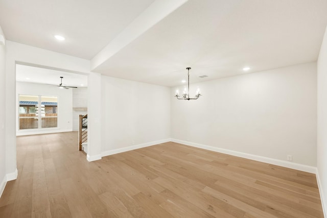 unfurnished room featuring ceiling fan with notable chandelier and light wood-type flooring