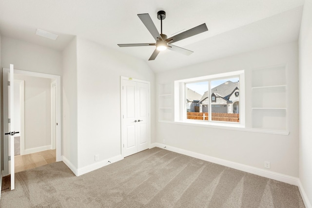 unfurnished bedroom featuring carpet, a closet, ceiling fan, and lofted ceiling