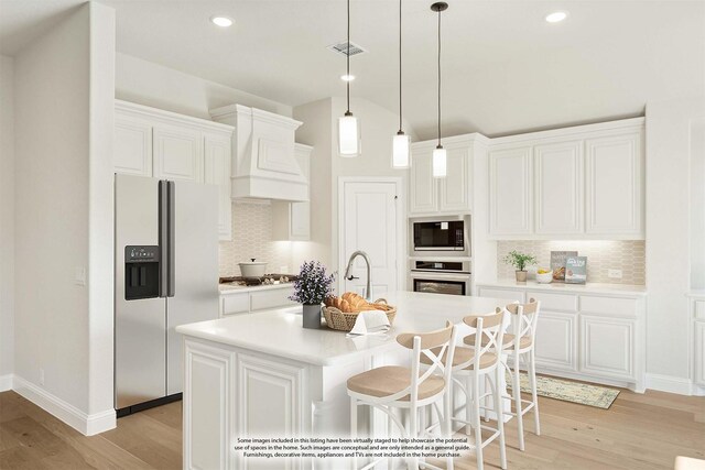 kitchen featuring a center island with sink, light hardwood / wood-style floors, white cabinetry, and stainless steel appliances