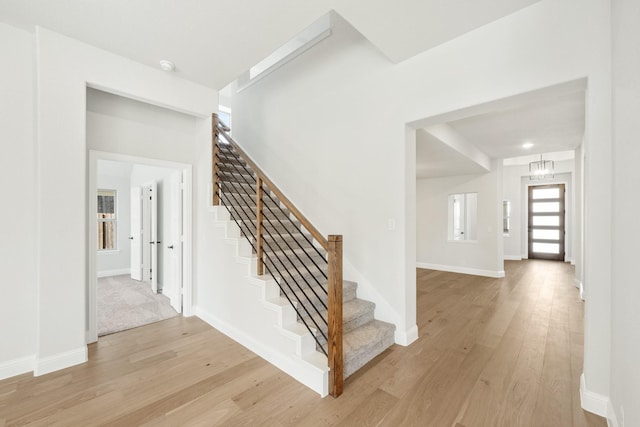 stairs with wood-type flooring and a notable chandelier