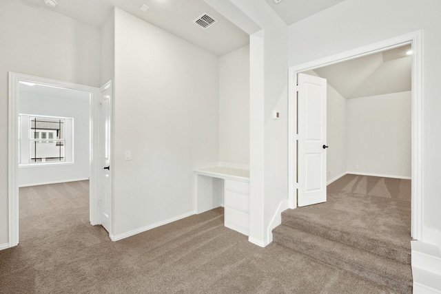 corridor with carpet floors and vaulted ceiling