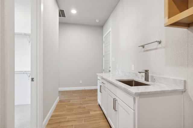 kitchen featuring light stone counters, sink, and white cabinets