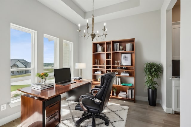 office area featuring hardwood / wood-style floors, a tray ceiling, and a notable chandelier