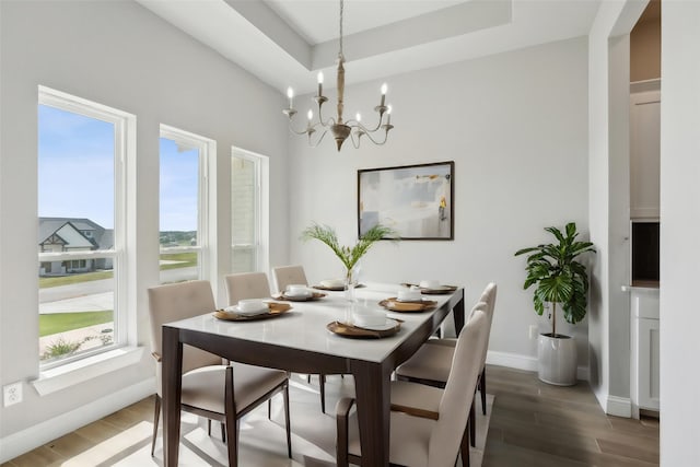 dining area featuring dark hardwood / wood-style floors, a notable chandelier, and a tray ceiling