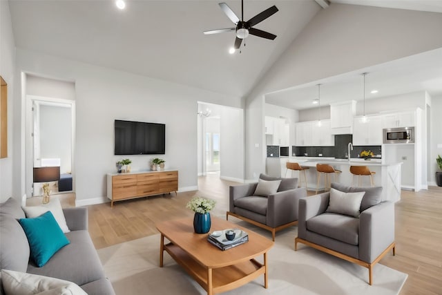 living room with sink, high vaulted ceiling, ceiling fan, and light wood-type flooring