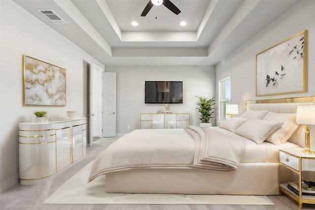 carpeted bedroom with ceiling fan and a raised ceiling