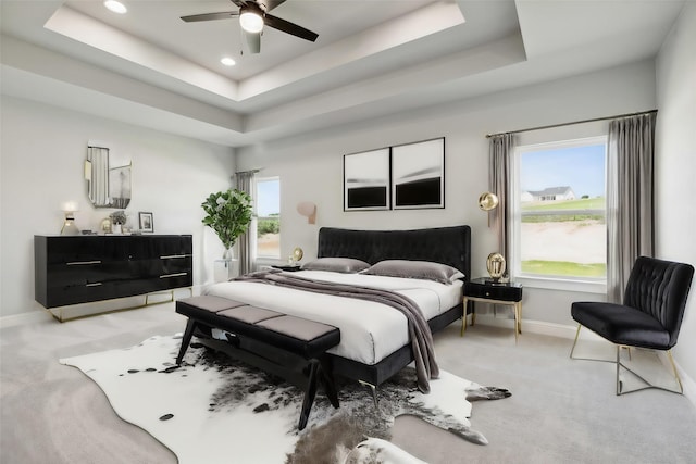 carpeted bedroom with multiple windows, ceiling fan, and a tray ceiling