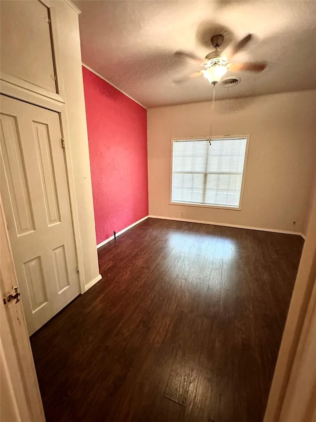 empty room with dark hardwood / wood-style flooring, a textured ceiling, and ceiling fan