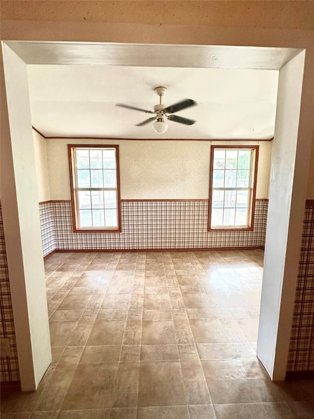 unfurnished room featuring ceiling fan, plenty of natural light, and ornamental molding