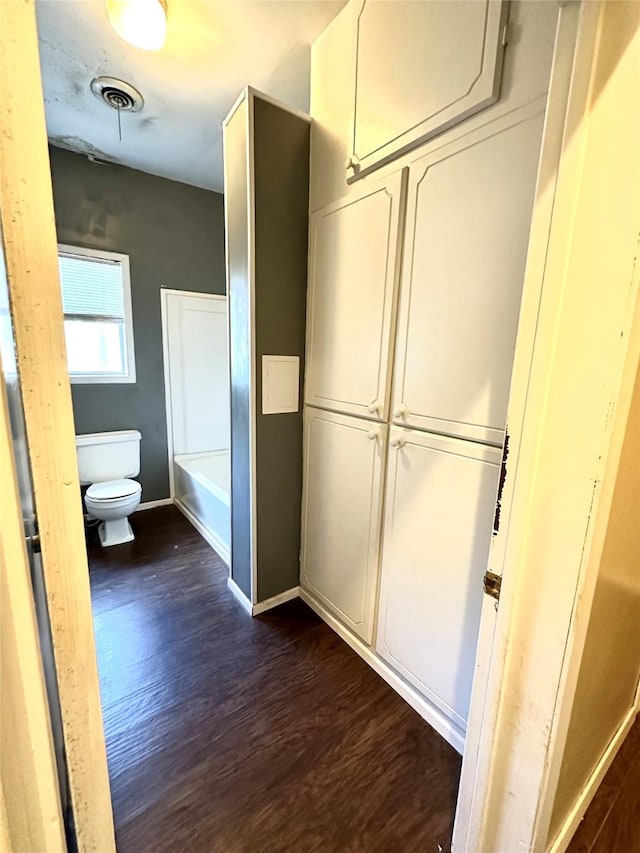 bathroom with a washtub, hardwood / wood-style floors, and toilet