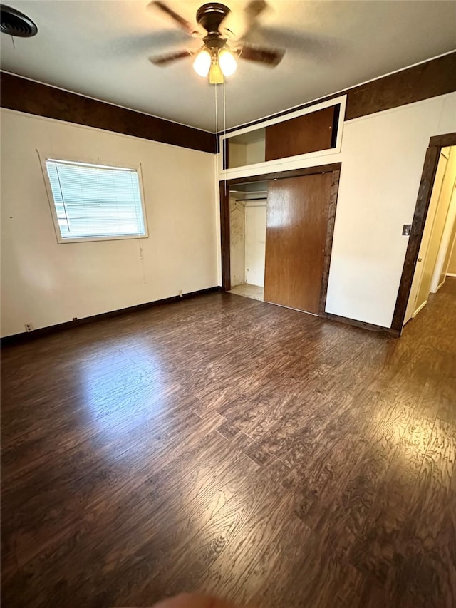 unfurnished bedroom featuring dark wood-type flooring, ceiling fan, and a closet