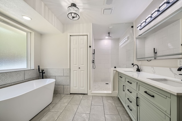 bathroom featuring independent shower and bath, dual vanity, tile patterned floors, and tile walls