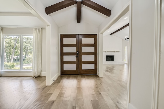 entryway with vaulted ceiling with beams, french doors, light hardwood / wood-style floors, a brick fireplace, and ceiling fan