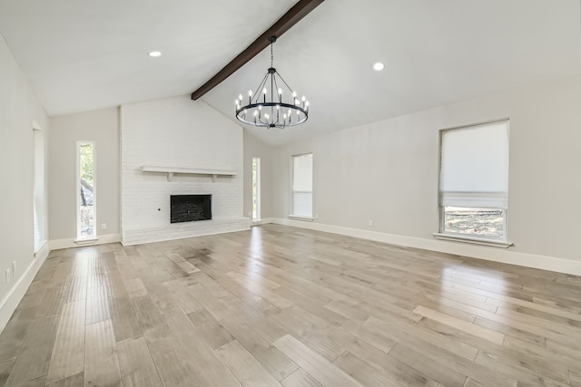 unfurnished living room featuring a chandelier, light wood-type flooring, beamed ceiling, brick wall, and a fireplace