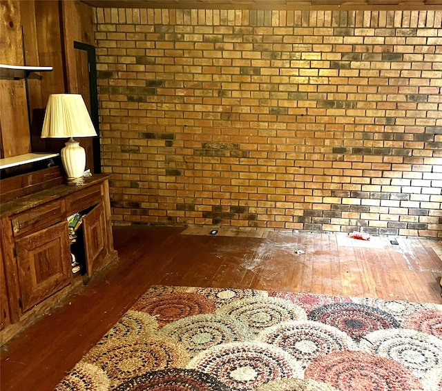 living room with brick wall and dark hardwood / wood-style floors