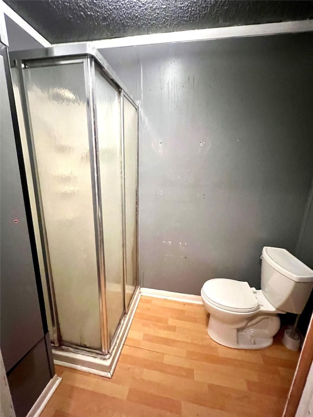 bathroom with a shower with door, wood-type flooring, and toilet