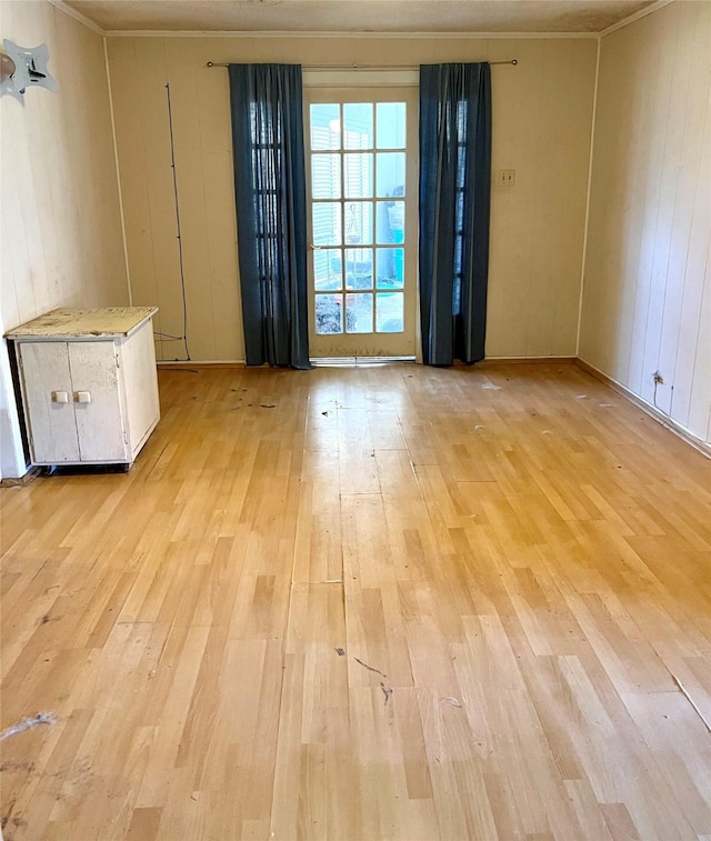 spare room with wooden walls and light wood-type flooring