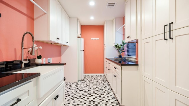 kitchen with white refrigerator, sink, and white cabinets