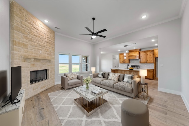 living room featuring ceiling fan, light hardwood / wood-style flooring, a fireplace, and ornamental molding