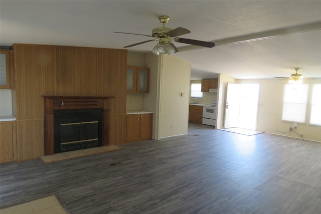 unfurnished living room featuring ceiling fan, vaulted ceiling, dark wood-type flooring, and sink