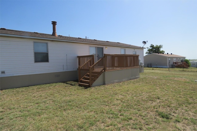 rear view of house with a wooden deck and a lawn