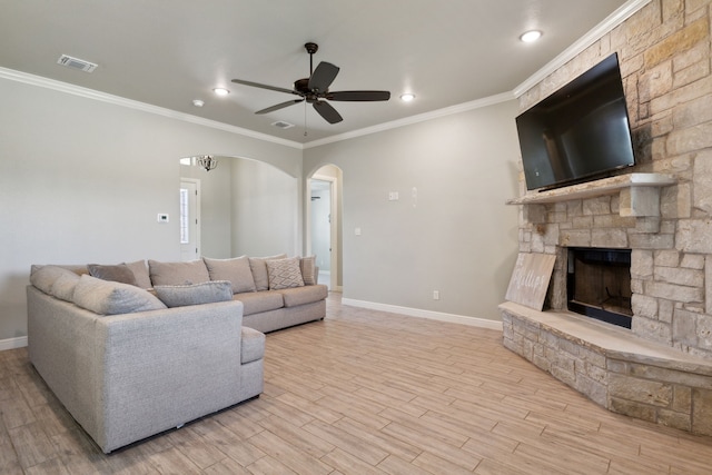 living room featuring a fireplace, crown molding, light wood-type flooring, and ceiling fan