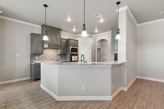 kitchen featuring tasteful backsplash, pendant lighting, light stone countertops, appliances with stainless steel finishes, and kitchen peninsula