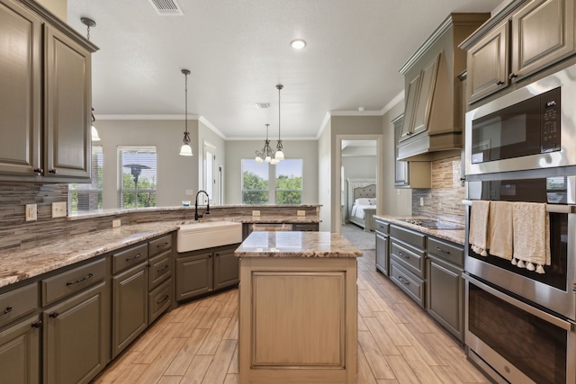 kitchen featuring a chandelier, a kitchen island, black appliances, decorative backsplash, and sink